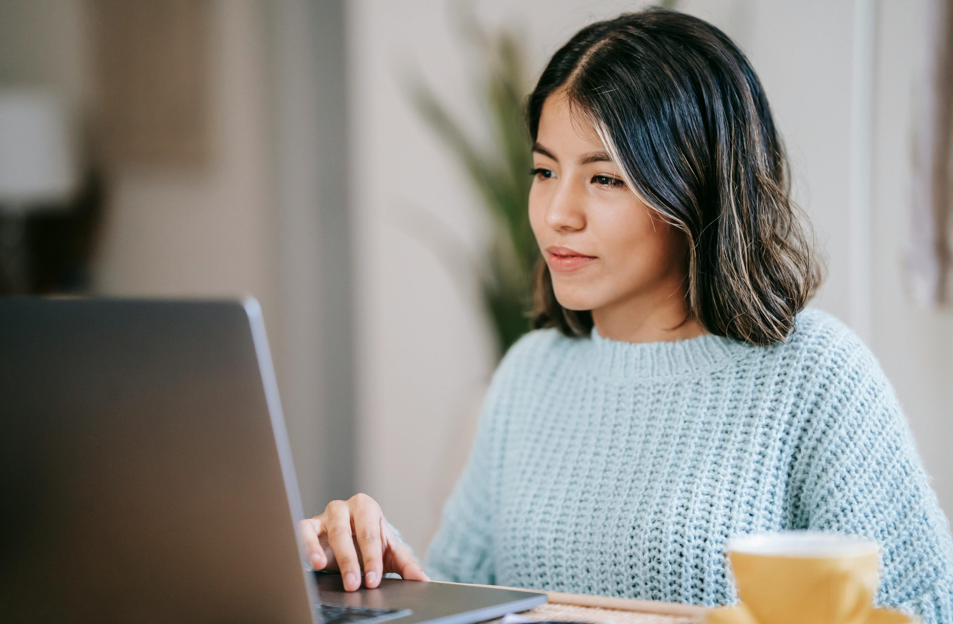 A woman sitting at a table using her laptop.