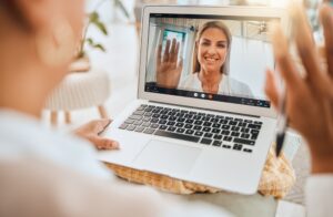 Video Counselling: Online Therapy. Laptop, video call and mental health with wave hello in virtual counseling consultation, doctor and patient in communication Psychologist, depression and women, trauma and anxiety, support and trust.