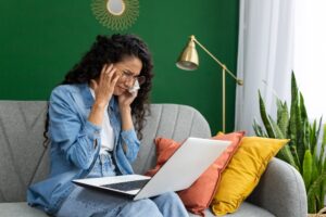 Video Counselling: Online Therapy. Online consultation with a psychologist, a psychotherapist, a crying woman sitting on a sofa in a living room with a laptop, talking remotely with a doctor, using a video call.