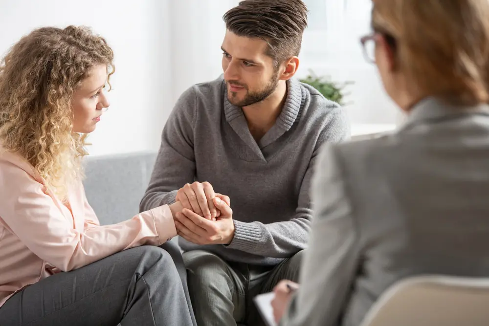 Relationship counselling. Young husband apologizing his worried wife during Relationship counselling therapy with counselor.