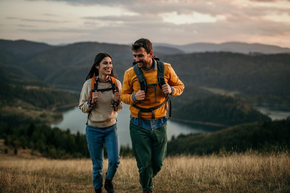 Trusted Relationship Counselling in St. Thomas. Shot of a couple going for a hike up the mountain, lake in the background.