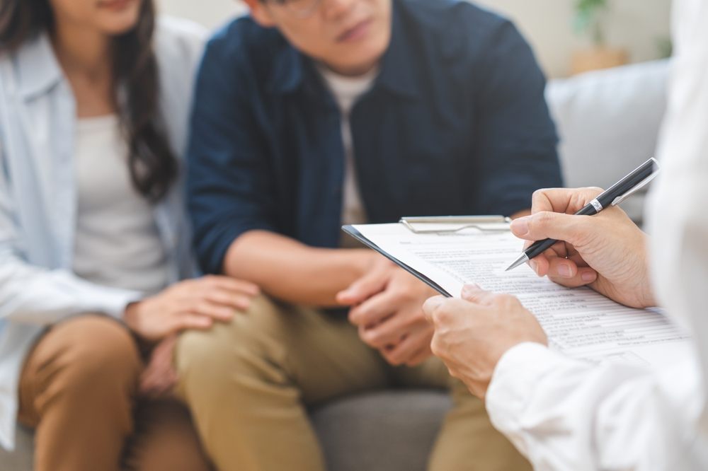 Grief Counselling. Psychology, depression asian young couple love, woman, man patient consulting problem mental health with psychologist, psychiatrist at clinic together, wife encouraging husband, therapy health care.